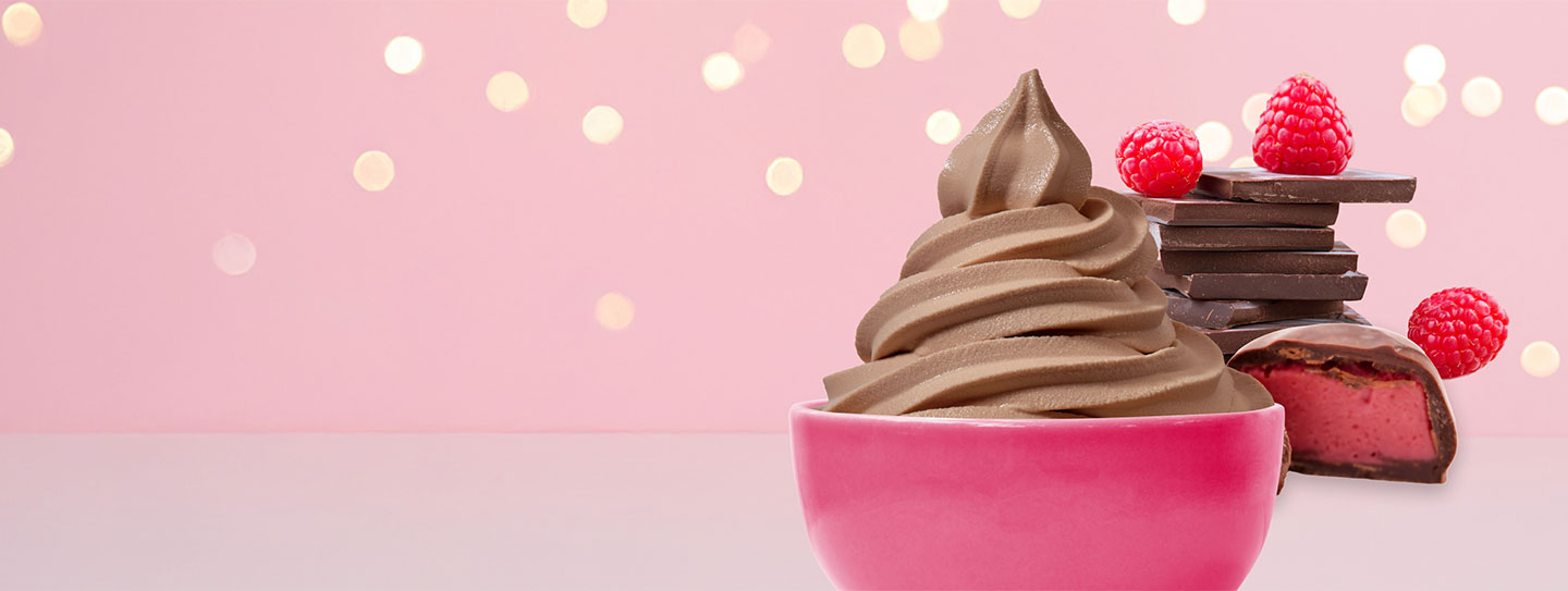 A cup of frozen yogurt alongside a cup of caffe mocha with a stick of peppermint candy.