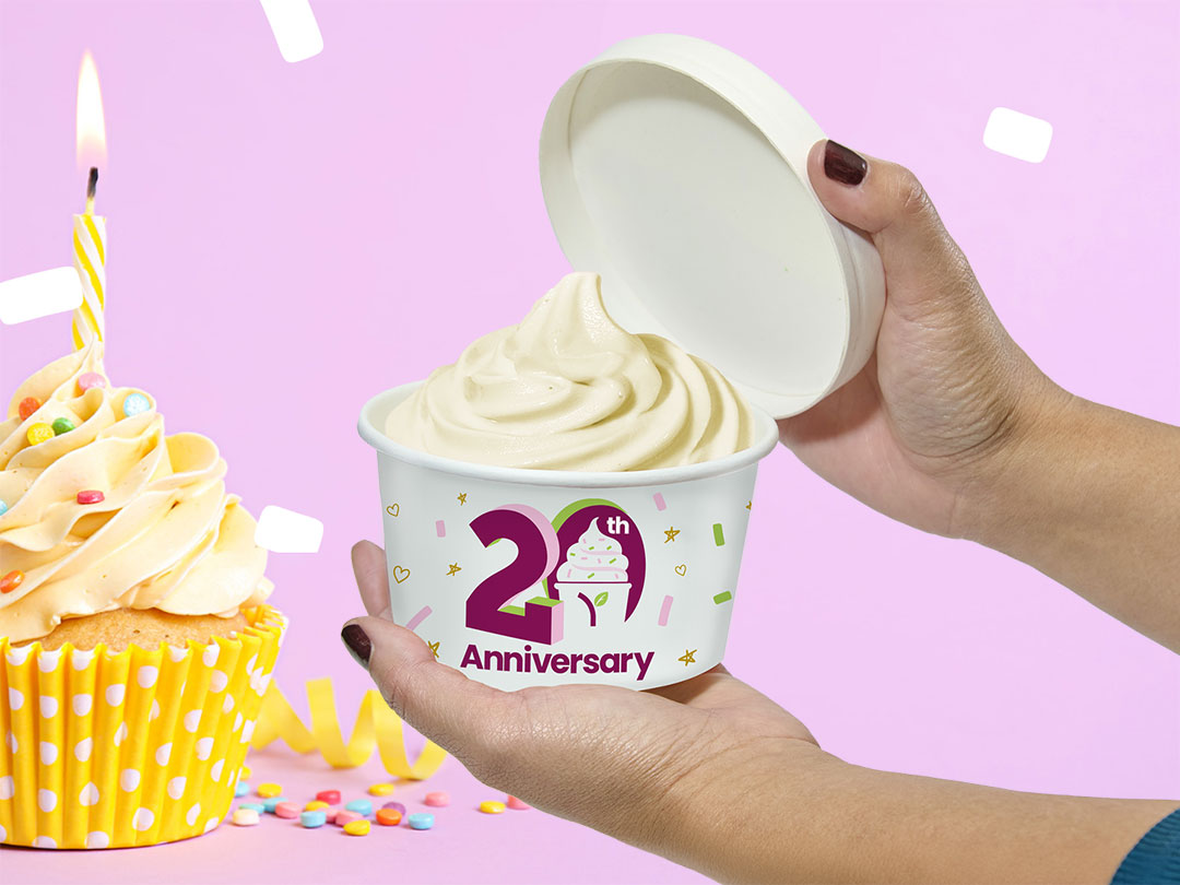 A cup of Yogurtland frozen yogurt alongside a cupcake with a birthday candle.