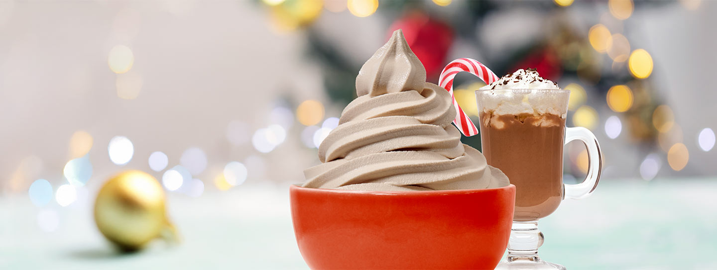 A cup of frozen yogurt alongside a cup of caffe mocha with a stick of peppermint candy.